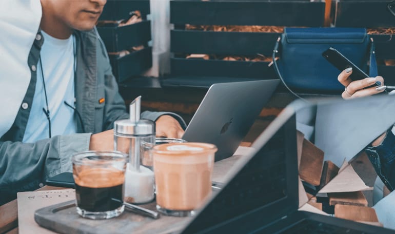 Kolleger sidder udenfor og arbejder ved laptops