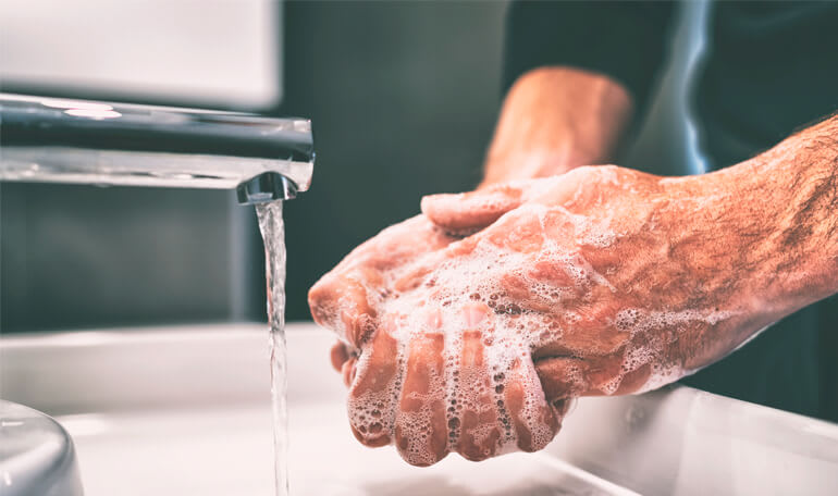 Person vasker hænder med sæbe under vandhane
