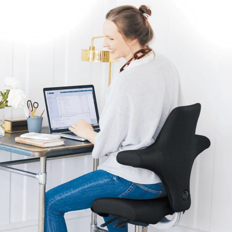 Kvindelig kollega sidder på Håg Capisco_Ergonomiske hjaelpemidler til din arbejdsdag_artikel