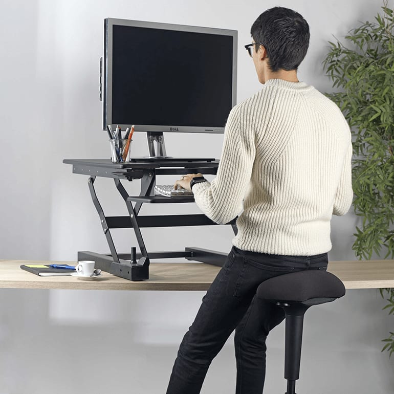 Mandlig kollega sidder på balancestol foran arbejdsstation