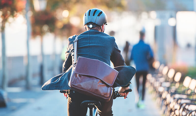 Person cykler på vej til arbejde med taske over skulder