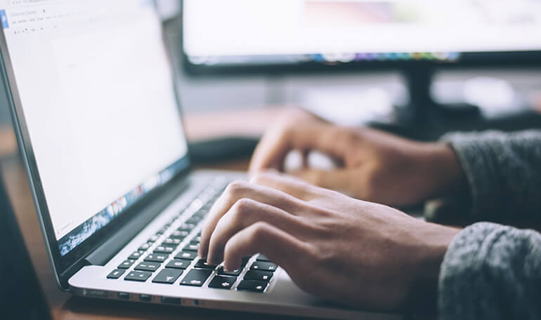 Mand skriver på computer_kom godt tilbage til hverdagen efter ferien_artikel