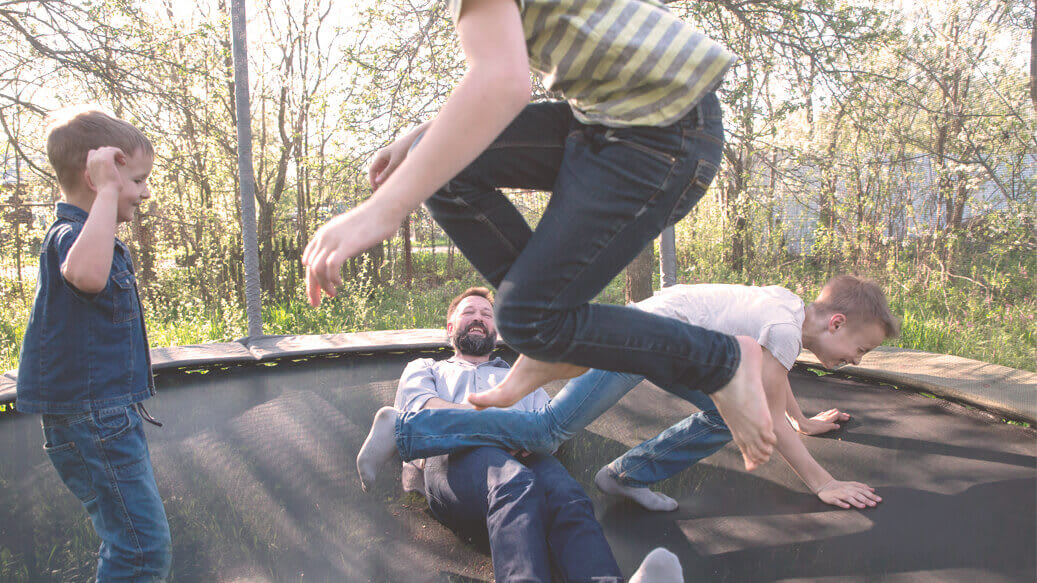 Far og børn på trampolin har det sjovt