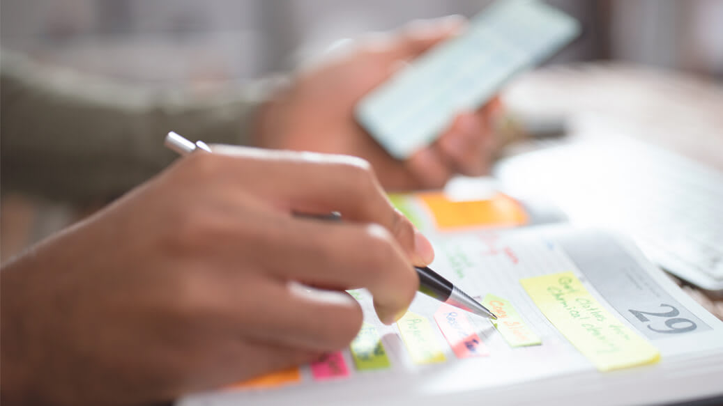 Person med mobiltelefon i haand skriver i sin kalender _hvilken kalender passer til mig_artikel