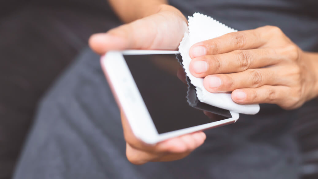 Person bruger mikrofiberklud på smartphone